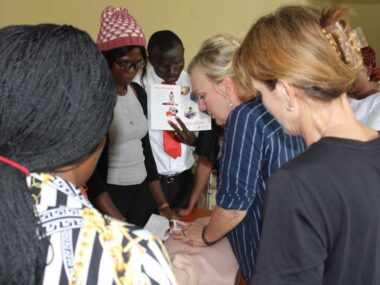 7-16-8 Pastor Gina demonstrating CPR on dummy for students standing around